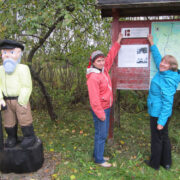 Kaigutsi külaseltsi juhatuse liige Tiina Veem (keskel) ja Kodukant Hiiumaa juhatuse esinaine Ester Tammis paigaldavad EV100 plaati, esiplaanil mõtlik Miku Kaarel.