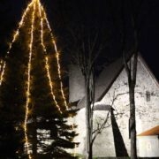 Valgustatud Käina kiriku müürid ja kuusepuu.