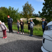 Pildil uurivad esimesse klassi minejad koos politseinik Kädu Aasmaga, kas seisva bussi tagant on näha maanteel liginev auto.